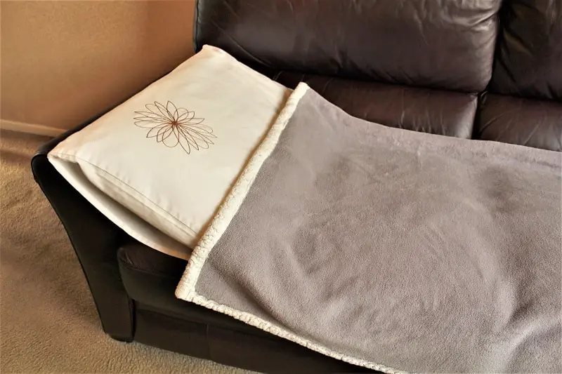 A pillow and blanket on a sofa, ready for someone to go couchsurfing.