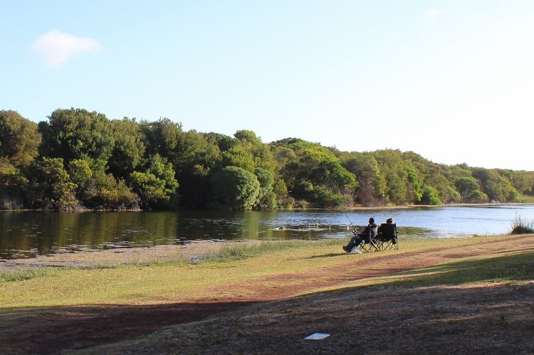 A couple on a bench looking out at a lake on an Adelaide to Melbourne road trip.