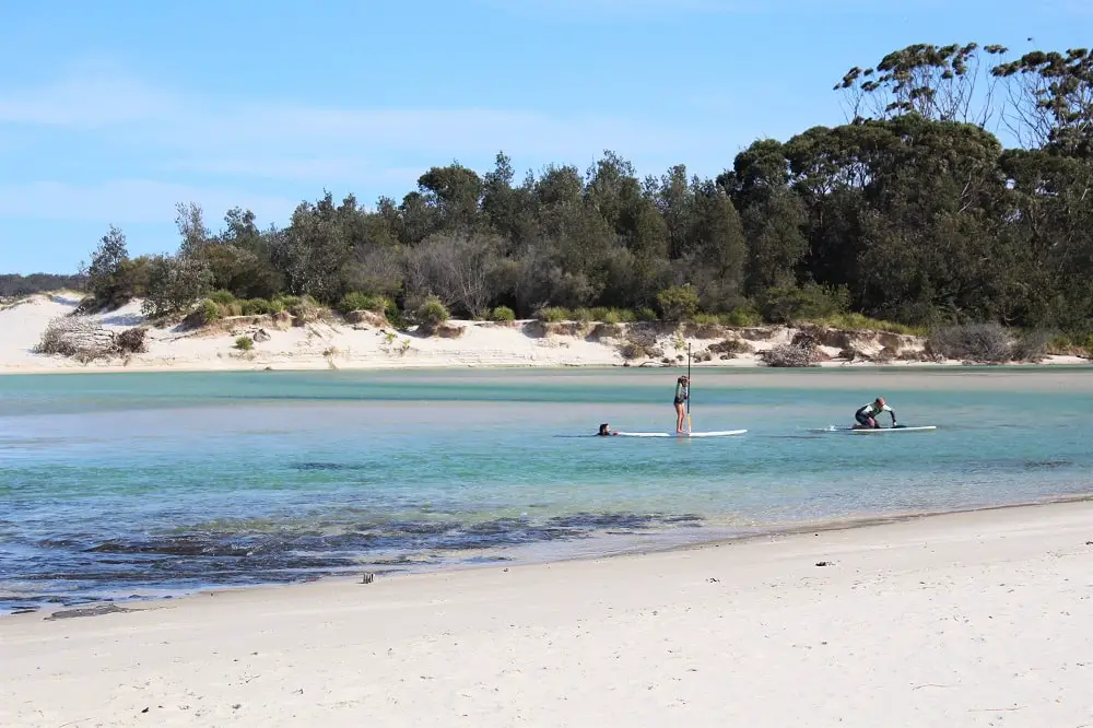 Kids paddleboarding at Moona Moona Creek: one of the top things to do in Jervis Bay, NSW.