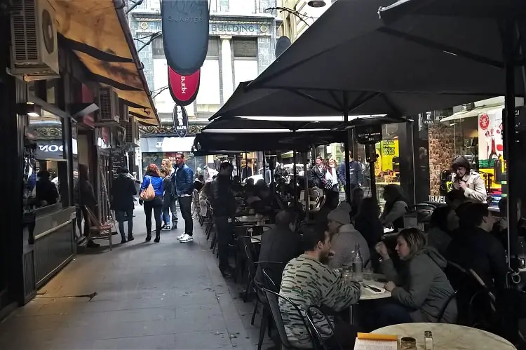 Melbourne laneway cafes with patrons sitting at outdoor tables.