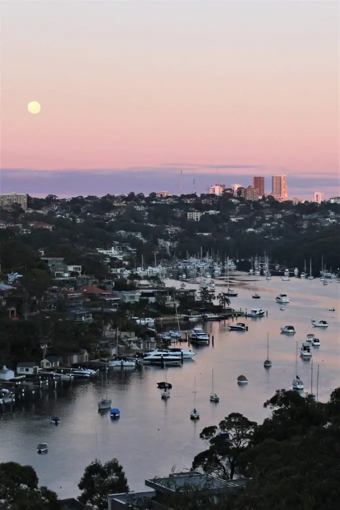 Moon setting over Middle Harbour at sunrise with a pink sky in Mosman Sydney.