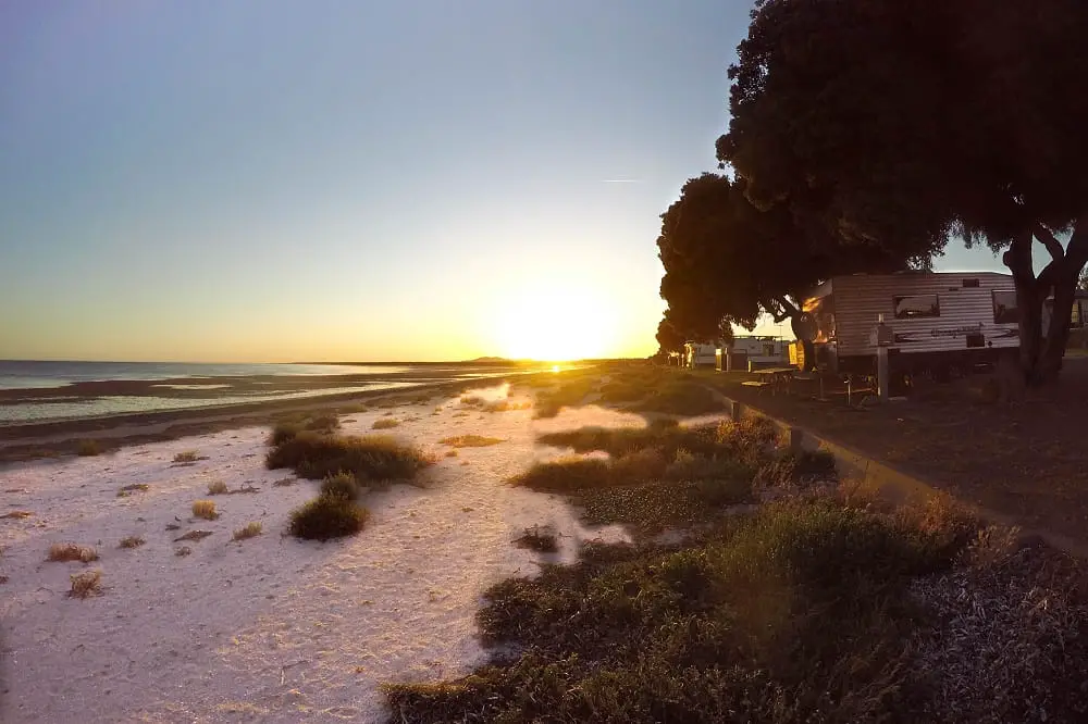 A caravan right next to the beach at Discovery Parks Whyalla at sunset.
