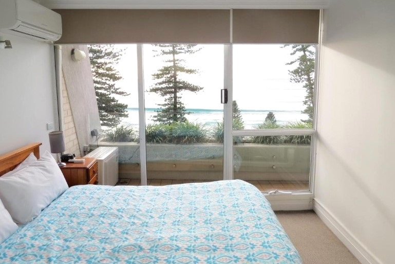 Double bed and ocean view balcony at Manly Paradise Motel and Apartments in Sydney, Australia.